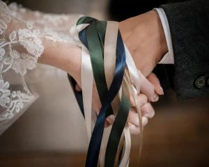 Ribbons tied around two joined hands during a hand-fasting ceremony.